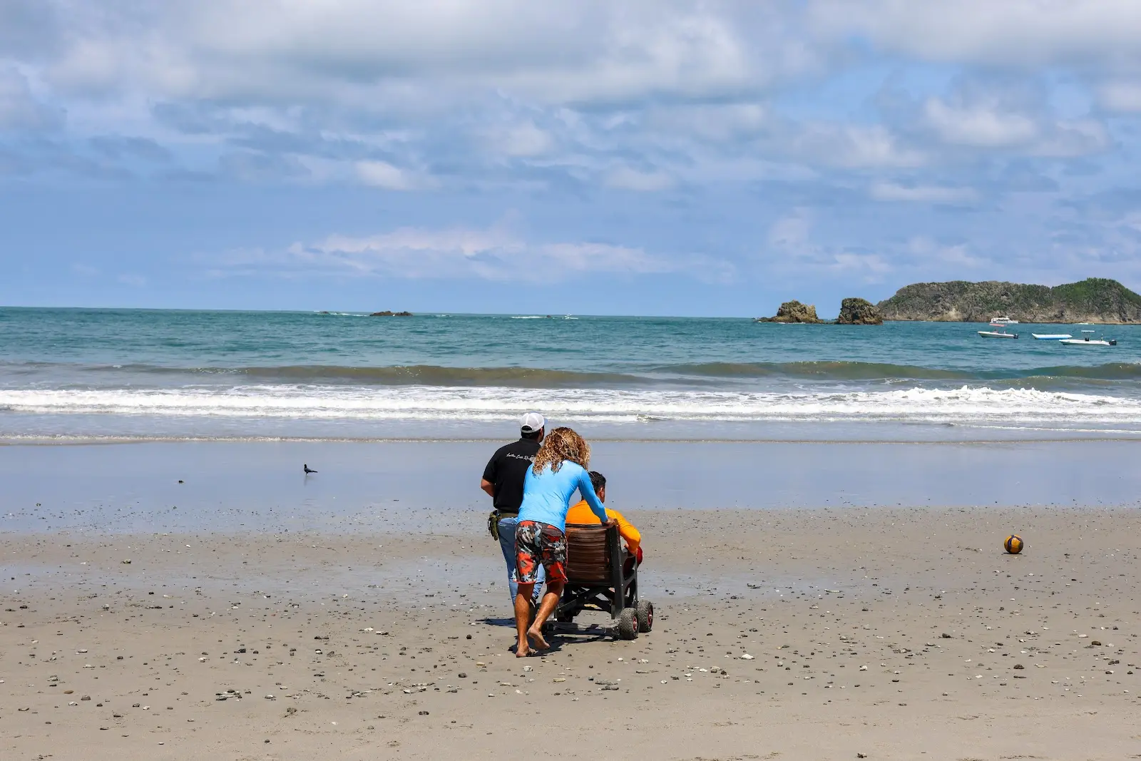 Una viajera en silla de ruedas en una playa de Costa Rica, frente al mar.