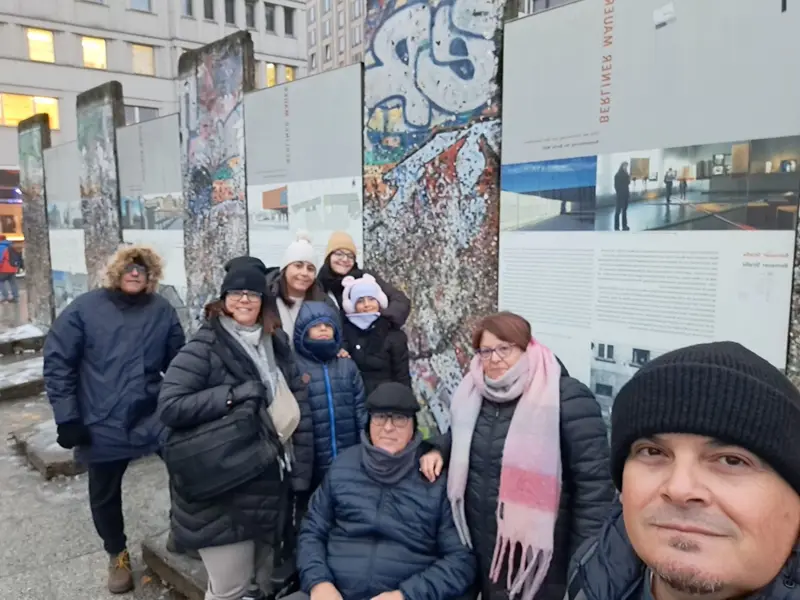 Una familia realizando un selfie con restos del muro de Berlin al fondo