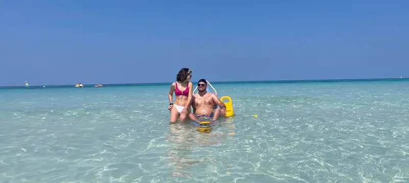 Un usuario de silla de ruedas con su pareja disfrutando del mar en Cuba en una silla anfibia