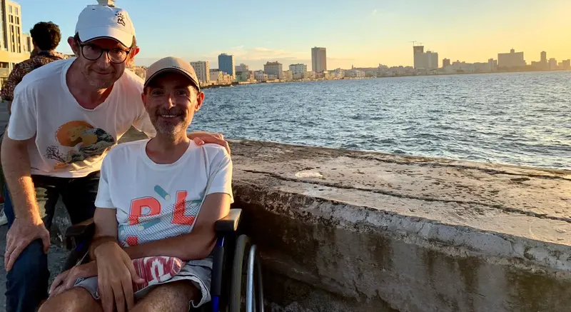 Dos personas, una de ellas usuaria de silla de ruedas, en el Malecón, en Cuba