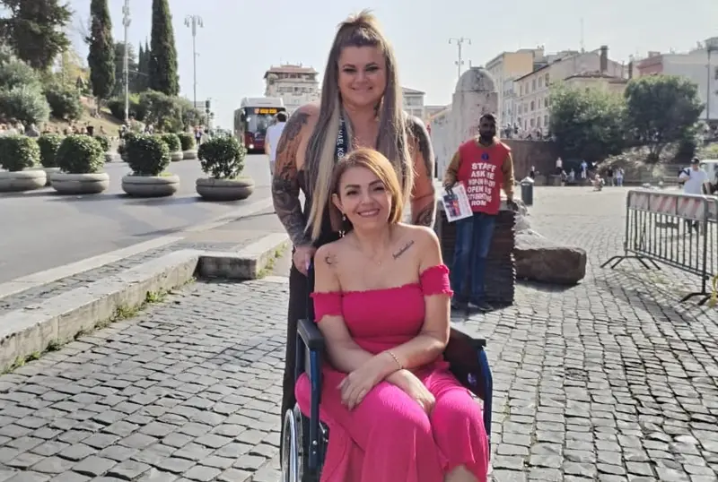 Dos amigas, una de ellas usuaria de silla de ruedas, en una calle de Roma