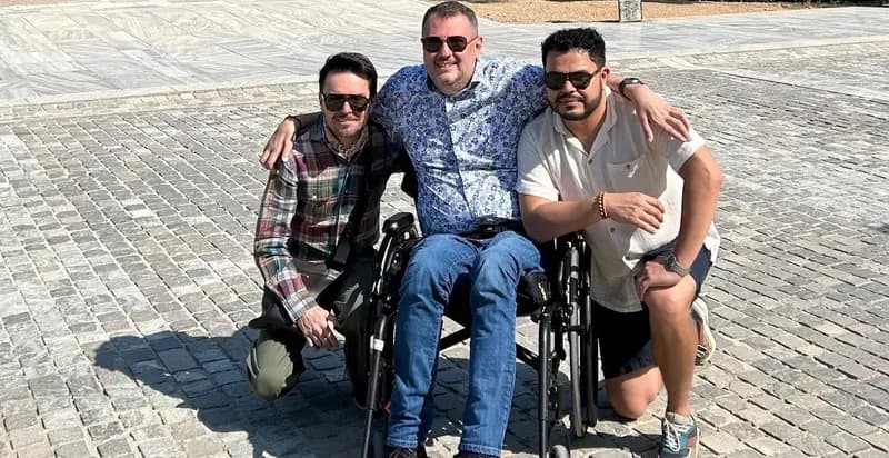 Una persona usuaria de silla de ruedas con dos amigos en Atenas