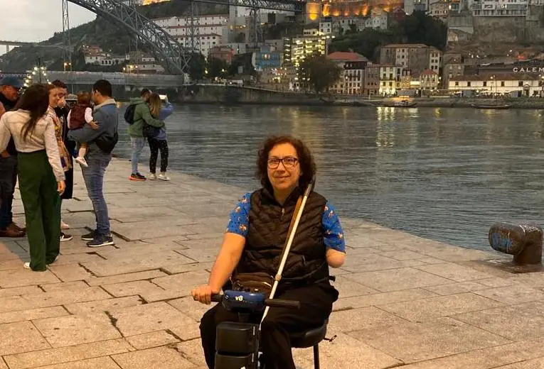 Una viajera con discapacidad en su scooter eléctrico con la ciudad de Oporto al fondo