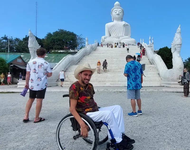 Viajero en silla de ruedas en un templo en Tailandia con un Buda al fondo