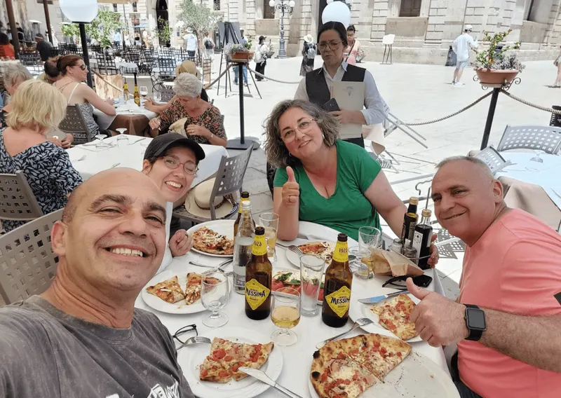 Cuatro personas comiendo pizza en Italia en silla de ruedas.