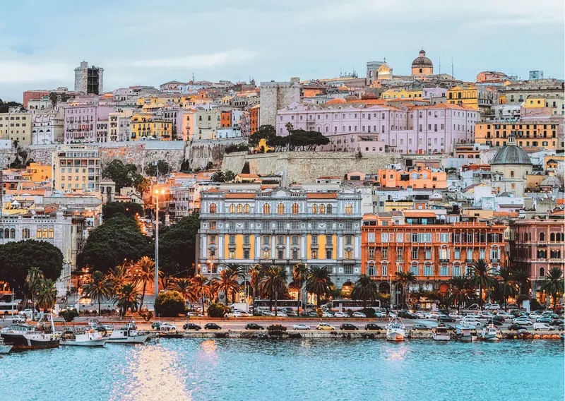 Imagen aérea desde el mar de Cagliari. Hay un primer plano de las casas características de esta zona de Italia precedidas por el paseo marítimo. Cagliari accesible a personas con discapacidad.