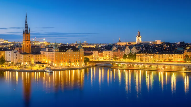 Imágen de Estocolmo tomada al atardecer dónde se ve la ciudad iluminada y sus reflejos en el mar.