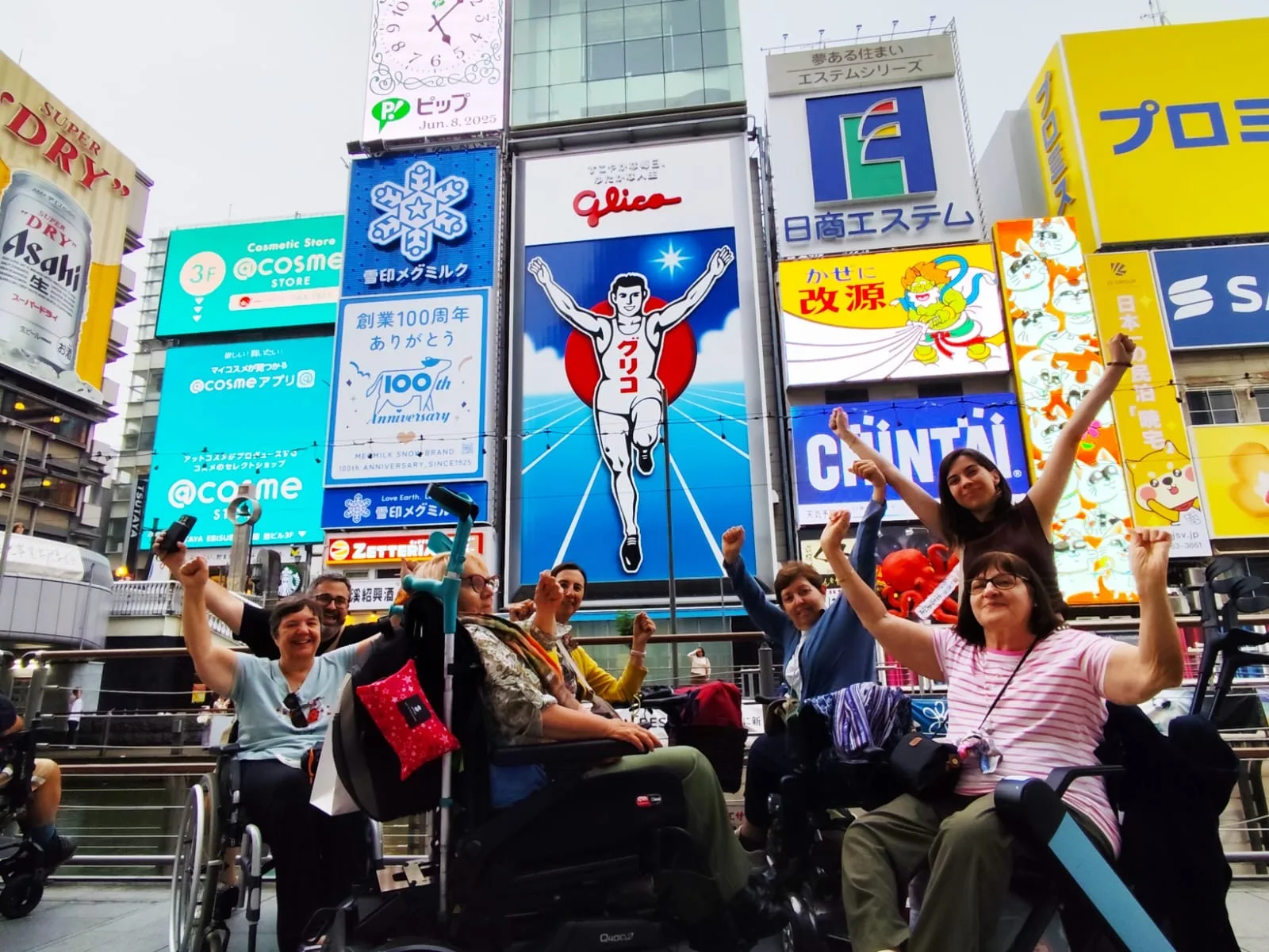 Calle comercial bulliciosa con rascacielos, carteles publicitarios luminosos y grupo de personas en silla de ruedas posando juntas en el centro de la ciudad.