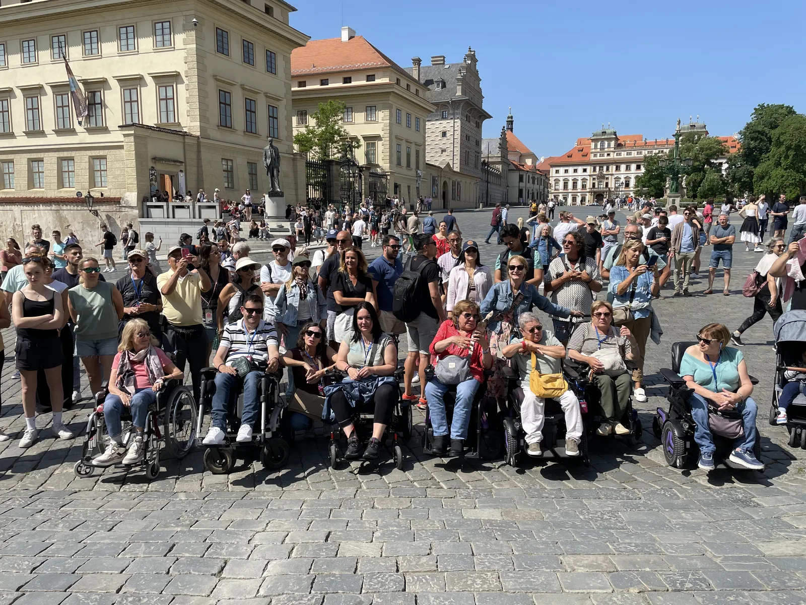 Plaza histórica con pavimento de adoquines, edificios coloniales de varios pisos. Personas en sillas de ruedas distribuidas en la plaza.